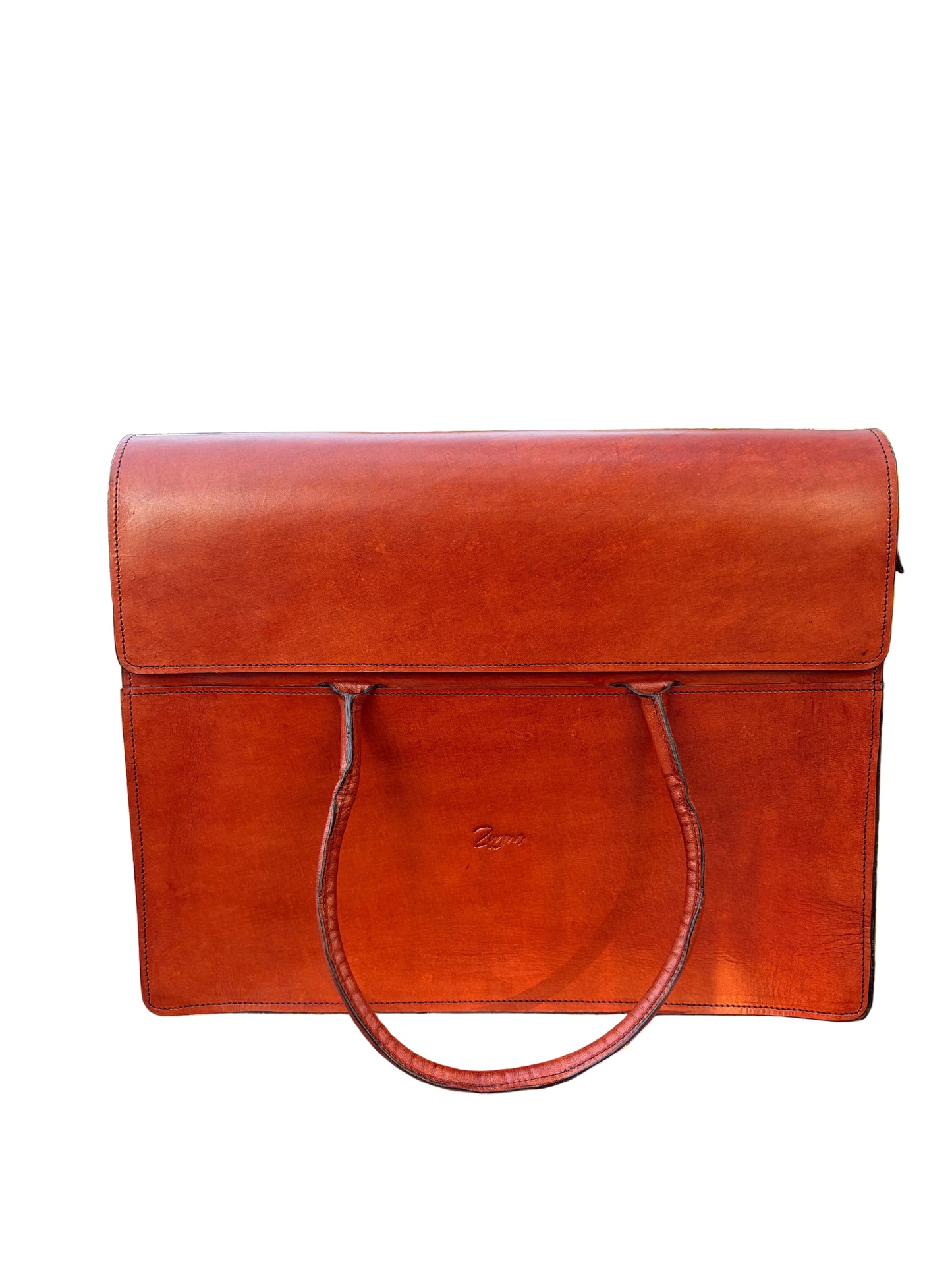 A reddish-brown leather briefcase or document bag with two handles, resting on a concrete ledge outdoors with palm trees and foliage in the background.