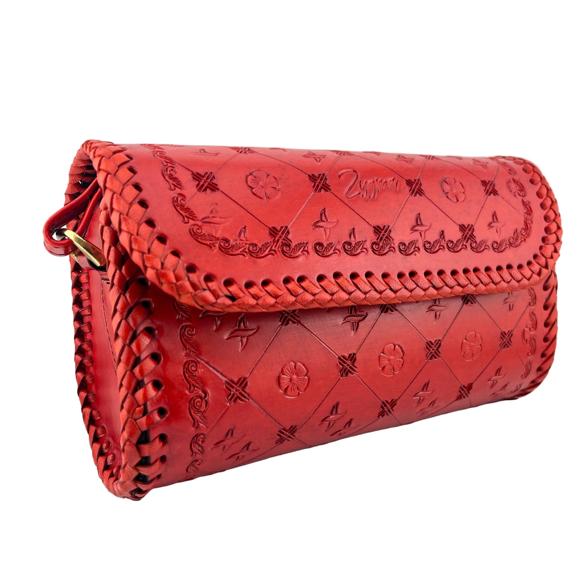 Red leather clutch bag with intricate patterns on a white background