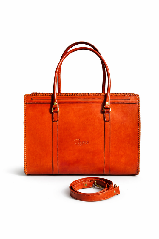 Orange leather handbag with matching strap on a white background